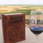 Copa de vino tinto y literatura en típico paisaje manchego