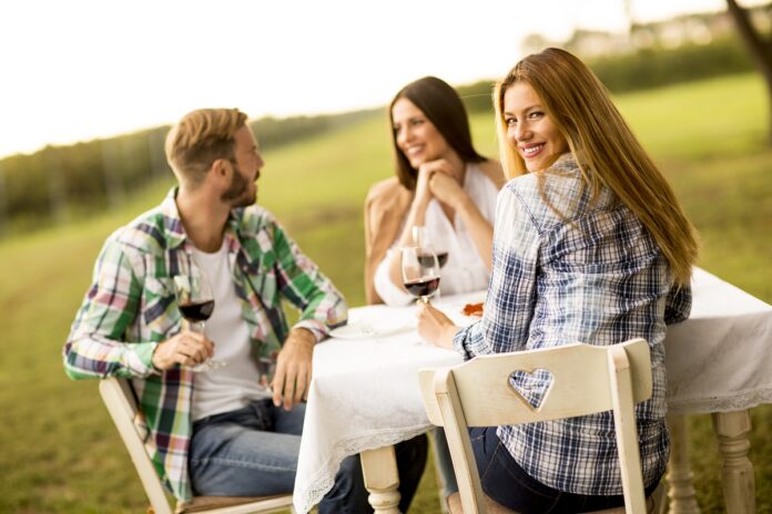 Group of young people drinking red wine in vineyard