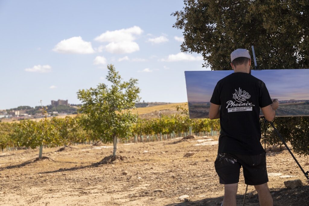 Un participante con su cuadro con las vistas de Belmonte al fondo